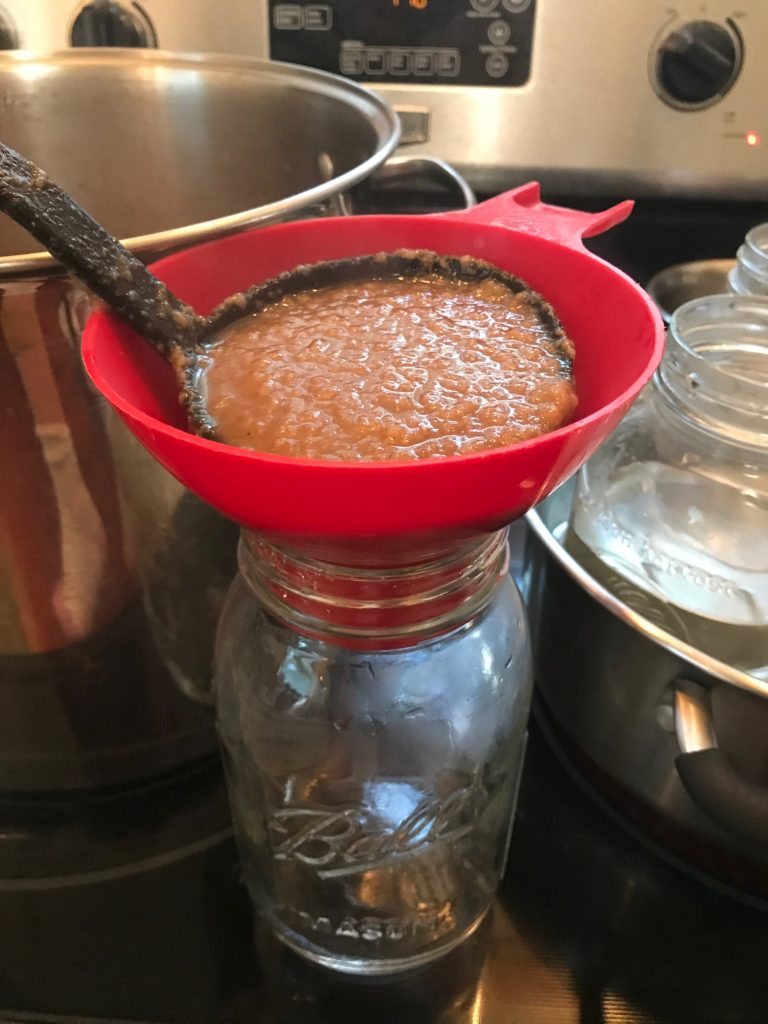 ladling pear sauce into hot jars