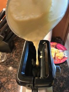 pouring the easy waffle batter into the waffle maker