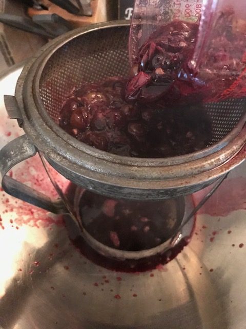 pouring the cooked grapes into a strainer