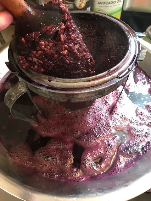 rolling the grapes through a strainer